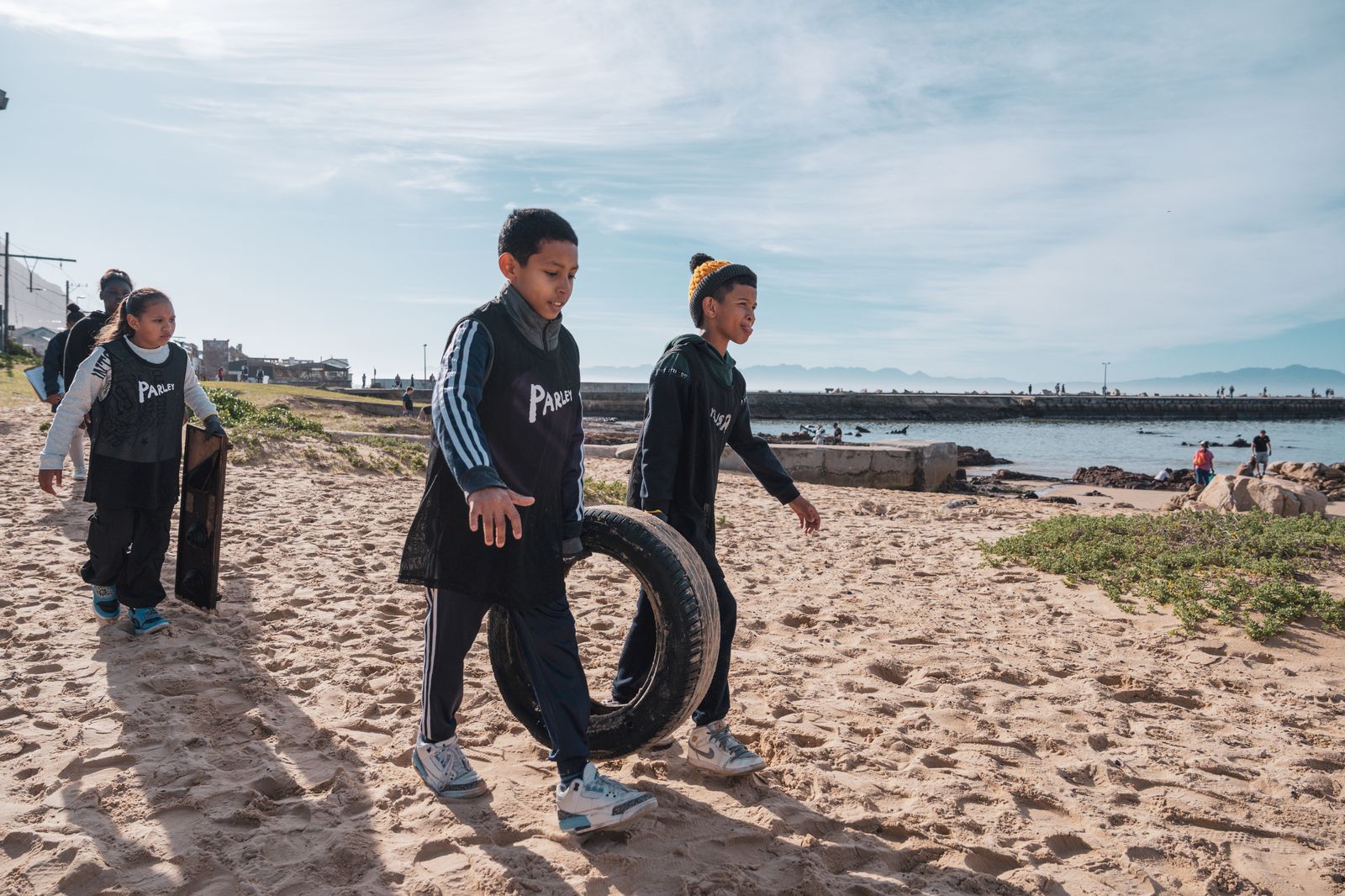 Children carrying a tyre off the beach during a clean-up