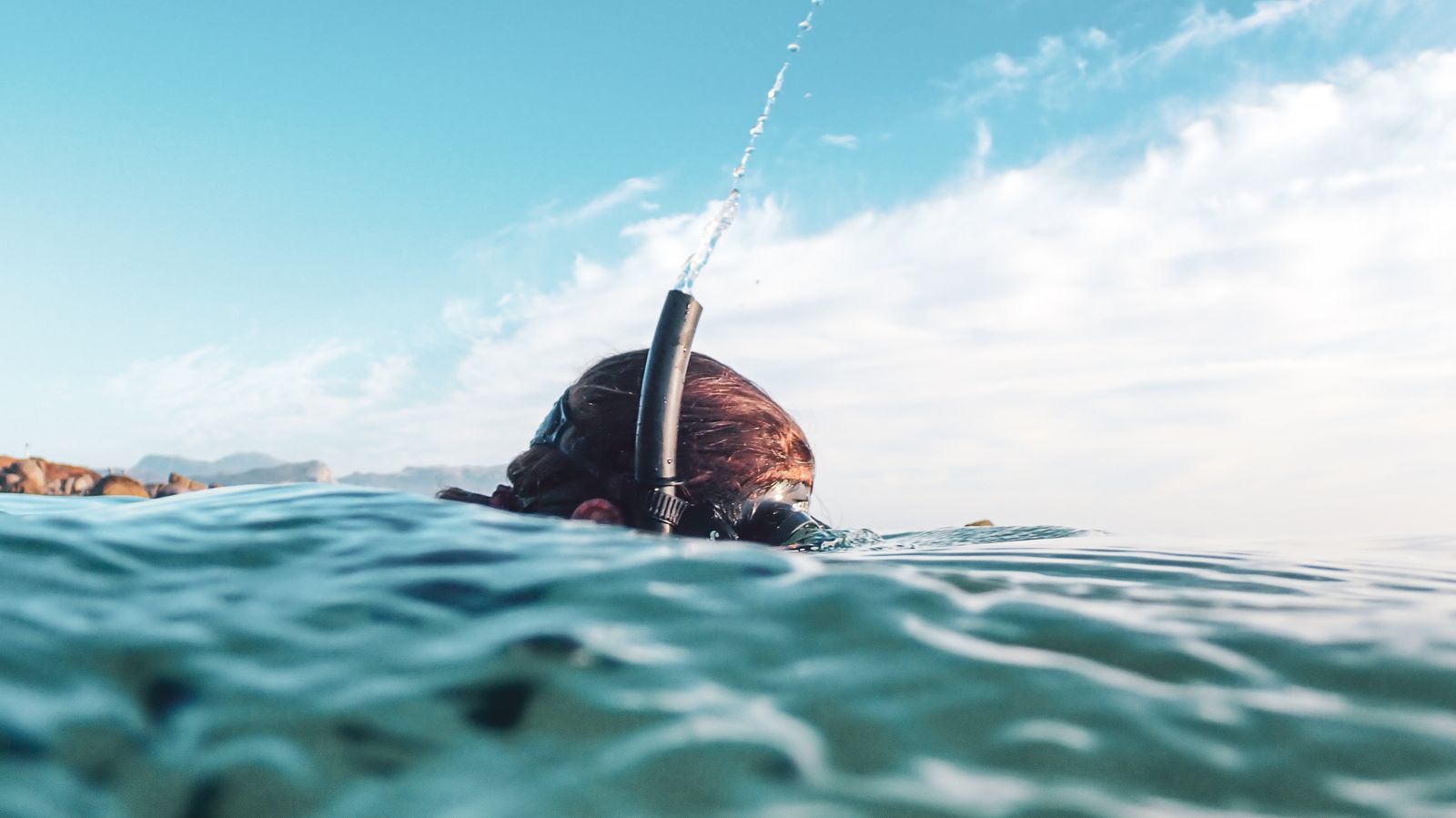 A snorkeller clearing her snorkel at the surface